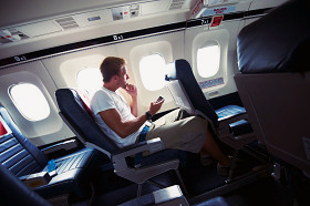 Guy Sits Texting in Window Seat of Small Airplane
